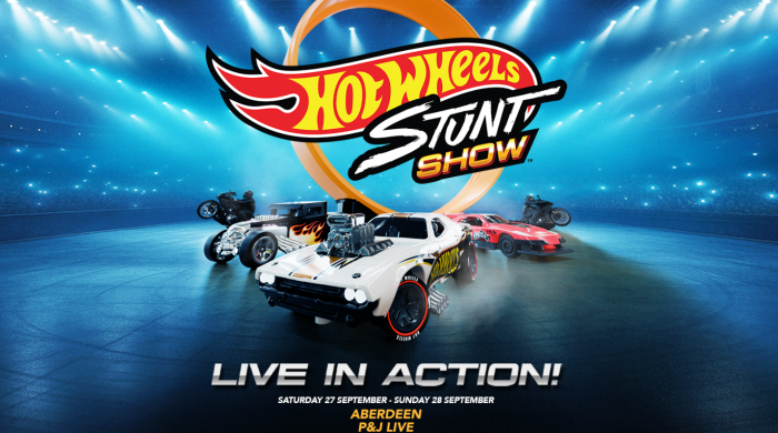 Some of the cars and bikes used in the Hot Wheels Stunt Show sitting in an arena.
